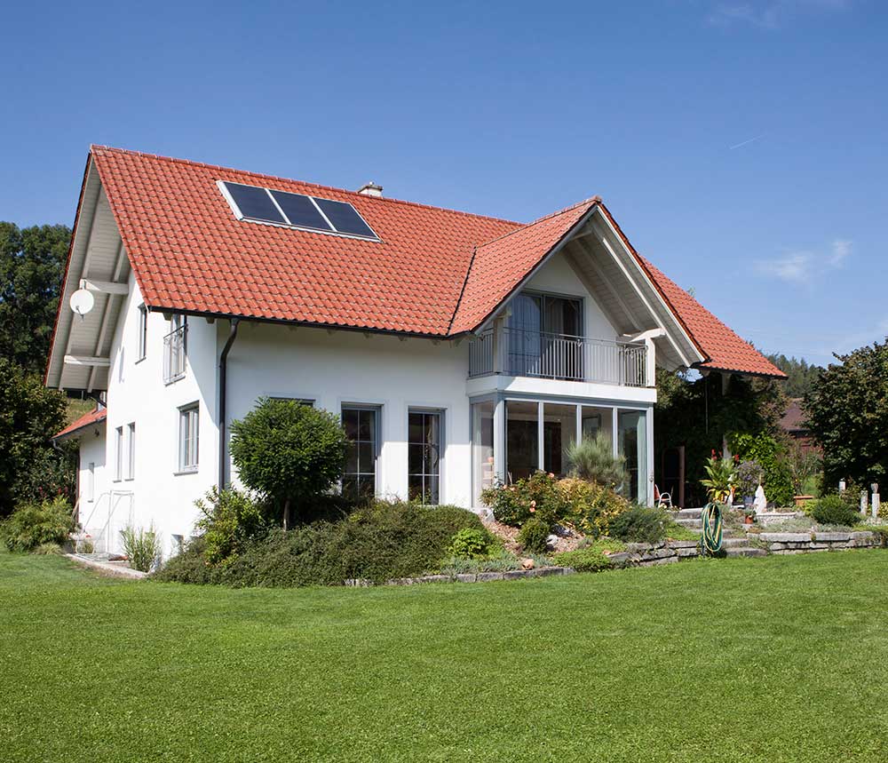 Beautiful mid-sized home, white with terra cotta colored roof and green lawn