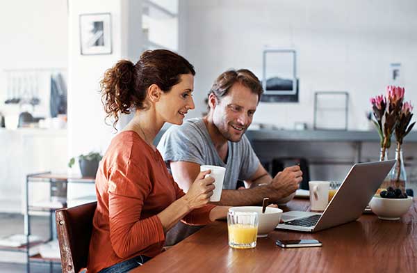 Husband and wife smiling looking at laptop