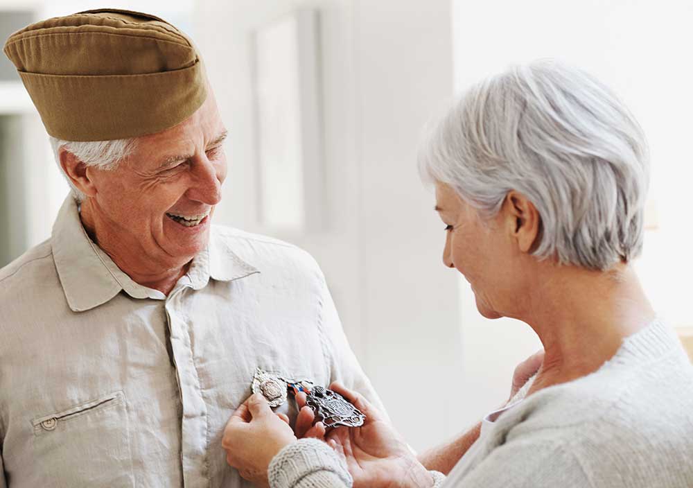 Senior couple smiling, woman admiring husband's military award